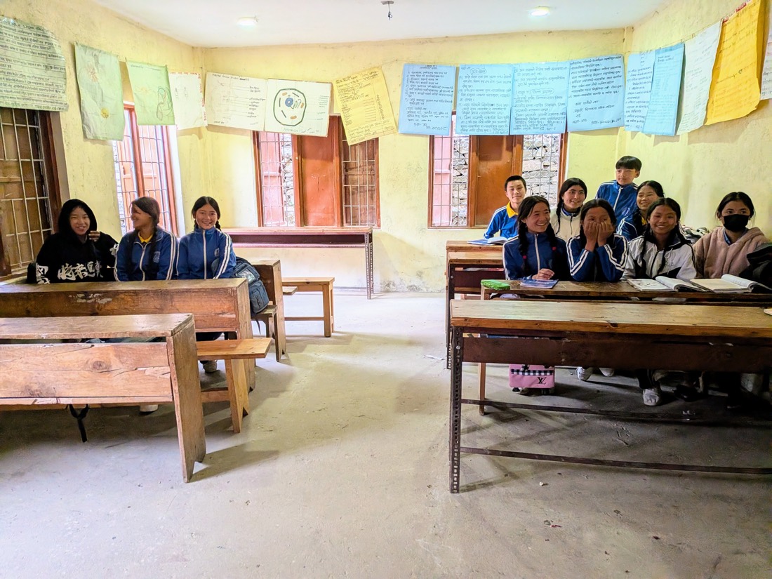Students smiling at their desks inside a Nepal classroom.