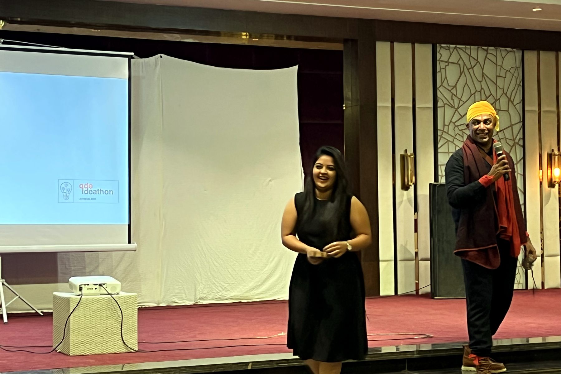 Two hosts on stage opening the QDE Ideathon