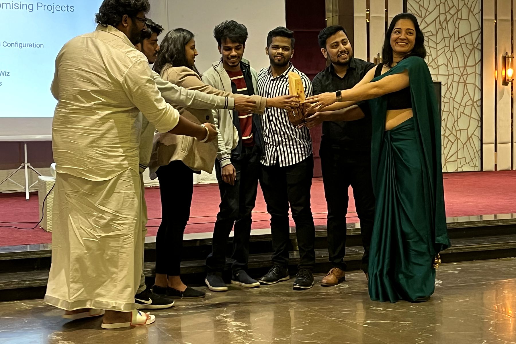 A winning team celebrating on stage with their trophy